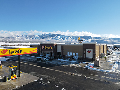 high rise photo of Love's exterior with snow on the ground and mountains in the background in Klamath Oregon