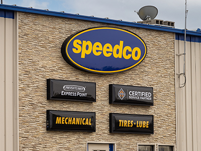 A photo of the exterior of a Speedco repair shop with various mechanical signs on the front