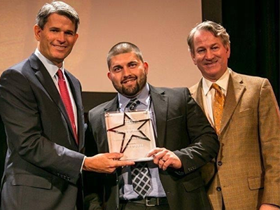 A man receiving an award from two other men. 